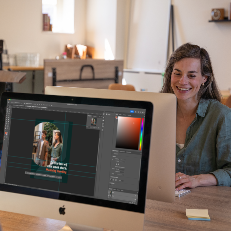Vrouw werkt achter een iMac met een ontwerp in Photoshop.