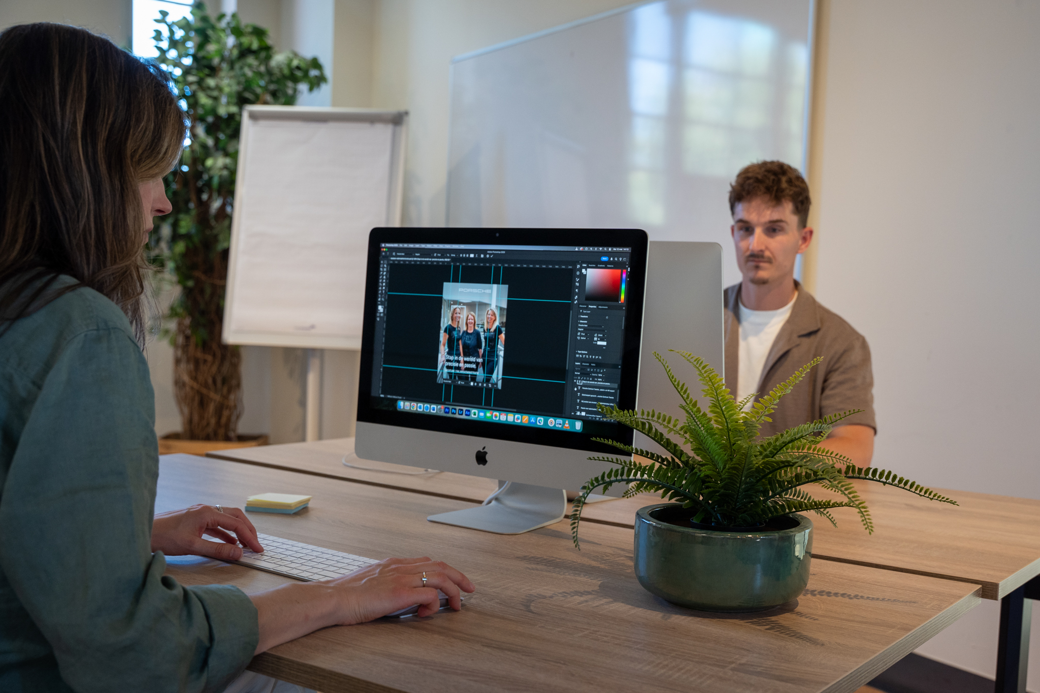 Collega’s werken samen aan een ontwerp op een iMac.